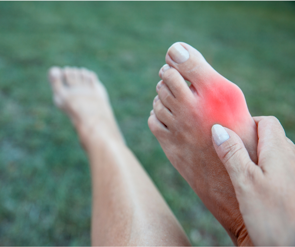 Person holding their foot with a reddened sole, indicating pain or discomfort in the area being pressed.